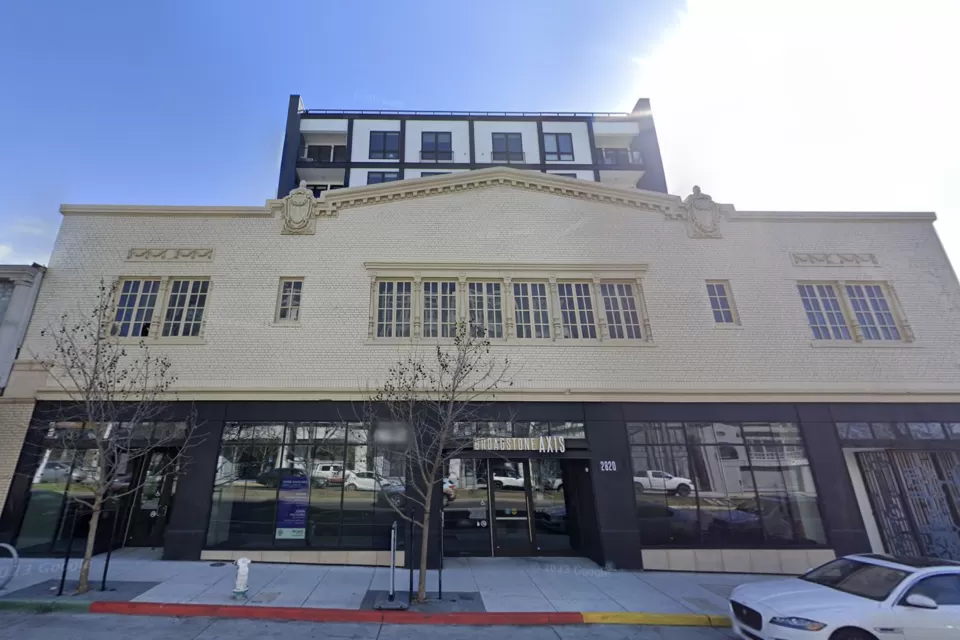Former auto showroom converted to apartments in Oakland, California with vintage facade and new tower rising above